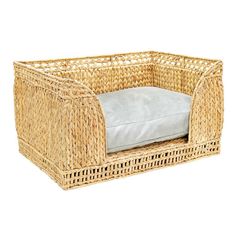 a dog bed made out of wicker with a pillow on it's side