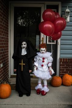 two people dressed up in costumes standing on the front porch with balloons and pumpkins