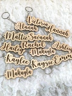 wooden keychains with names on them sitting on a white surface, one has a name tag attached to it