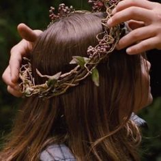 a woman with long hair wearing a crown made of branches and flowers on her head