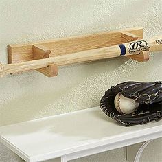 a baseball bat, glove and ball on a shelf in the corner of a room