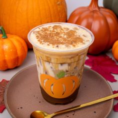 there is a cup of ice cream on the plate with pumpkins and leaves around it