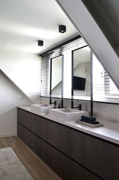 a bathroom with two sinks under a slanted ceiling