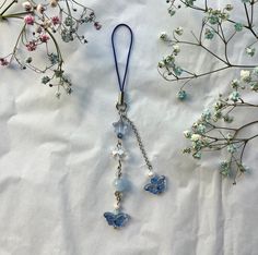 the necklace is attached to a chain with butterflies on it and flowers in the background