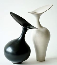 two black and white vases sitting next to each other on a table with a white background