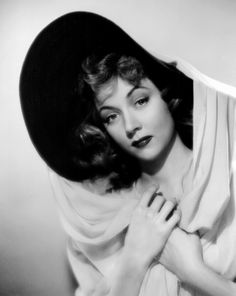 black and white photograph of a woman wearing a hat with her hands on her chest