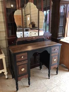 an antique desk and mirror are in a room with other furniture, including a dresser