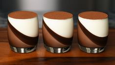 three brown and white glasses sitting on top of a wooden table next to each other