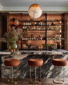 an elegant bar with marble counter tops and gold stools