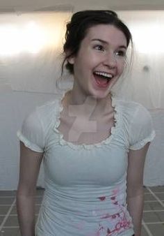 a woman is laughing while standing in front of a wall with tile floors and white walls