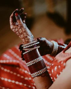 a woman with henna on her hand and bracelets around her wrist, holding something in the other hand