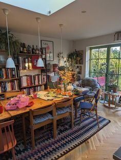 a dining room table with chairs and bookshelves in front of a large window