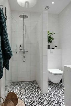 a white bathroom with black and white floor tiles on the shower wall, toilet and sink