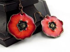 two red flowers are hanging from earrings