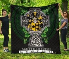 two women holding up a blanket with an image of the coat of arms on it