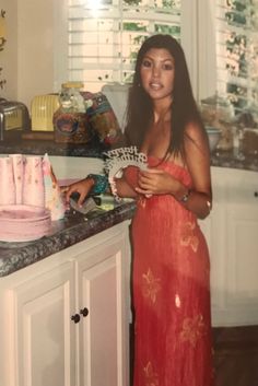 a woman in a red dress standing next to a counter with cakes on it and the words 4 photos of kourt through the years