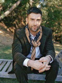 a man sitting on top of a wooden bench wearing a suit jacket and neck tie