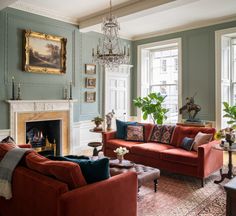 a living room filled with furniture and a chandelier hanging from the ceiling over a fire place