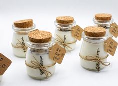 small jars filled with white candles and tied with twine, labeled with the names of each candle