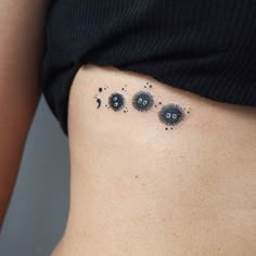 a woman's stomach with small black dots on it and an eyeball tattoo