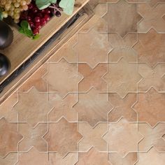 an overhead view of a tile floor with grapes and other items on it, including a bowl of fruit