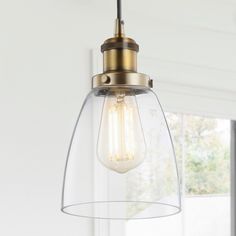 a light fixture hanging from the ceiling in a room with white walls and windows behind it