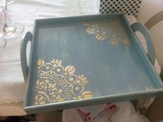 a blue tray with gold designs sitting on top of a table next to wine glasses