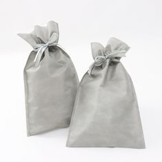 two gray bags with bows on them sitting next to each other in front of a white background