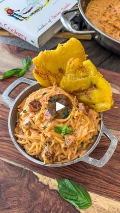 some food that is in a pan on a wooden table next to other foods and utensils