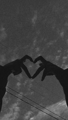 two giraffes making a heart shape with their hands in the air against a cloudy sky