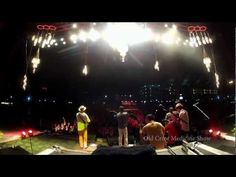 a group of people standing on top of a stage with lights in the dark behind them