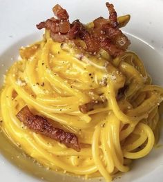 a white plate topped with pasta and bacon