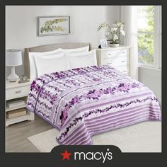 a purple and white bedspread on a bed in a room with a window