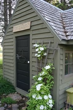 a small shed with flowers growing on the side