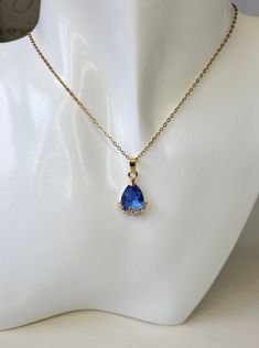 Beautiful Royal blue waterdrop rhinestone glass crystal pendant necklace. The elegant and sparkly pendant is set in a pretty gold flower decoration at the bottom and comes on a gold coloured stainless steel neck chain (45cms adjustable) with lobster clasp fastener. Glamorous evening and special occasion wear this necklace will add the finishing touch to your party outfit. Will make a perfect gift for bridesmaids, Christmas, birthstone, anniversary idea for wife, girlfriend or any lady in your li Blue Gold Necklace, Gold And Blue Necklace, Teardrop Crystal Rhinestone Necklace For Gift, Elegant Blue Teardrop Drop Necklace, Cubic Zirconia Teardrop Pendant Drop Necklace For Party, Cubic Zirconia Teardrop Pendant Necklace For Parties, Elegant Gold Drop Crystal Necklaces, Elegant Blue Rhinestone Necklace Gift, Gold Teardrop Necklace With Sparkling Stones