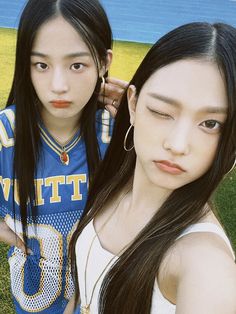 two young women standing next to each other in front of a blue and yellow field