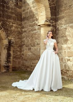 a woman in a white wedding dress standing by an old building