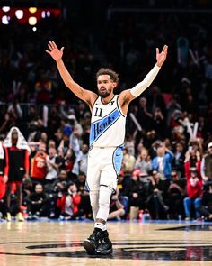 a basketball player with his arms in the air and hands out as he walks down the court