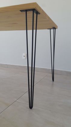 a wooden table with black hairpinks on it's legs in an empty room