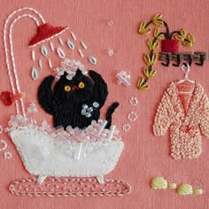 some items are laying out on a pink table cloth and one has a black cat in a bathtub