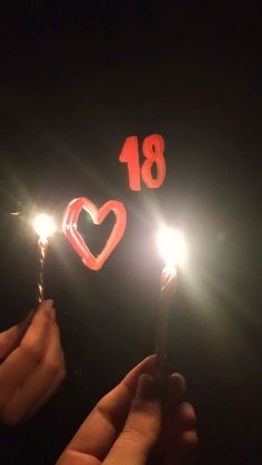 someone holding a sparkler with the number eighteen on it and a heart shaped candle