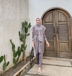 a woman standing in front of a door wearing a hijab and holding an umbrella