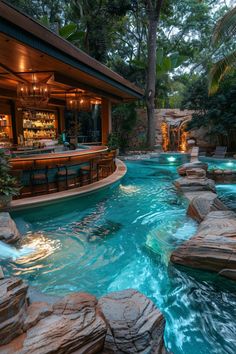 an outdoor bar and pool in the middle of a tropical setting with waterfalls, rocks, and water features