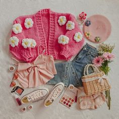 the contents of a pink knitted sweater laid out on a white surface