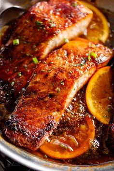 some meat and oranges are in a pan on the stove with seasoning sprinkled around them