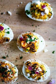 several deviled eggs with various toppings on a wooden table