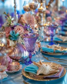 the table is set with purple and blue dishes, silverware, and seashells