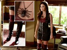 a woman standing in front of a mirror wearing thigh high boots and a spider necklace