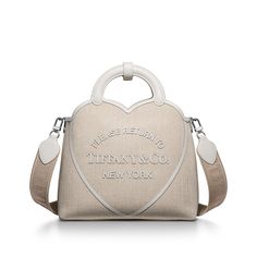 Inspired by one of the House’s most distinctive designs, the heart-shaped Return to Tiffany™ handbags are crafted in supple leather that nods to our iconic jewelry. Add a playful touch to every day with this small tote. It features our signature heart motif and a detachable leather strap. An interior zip pocket keeps essentials organized. White canvas; 11.4" W x 13.7" H x 4.3" D; Palladium-plated hardware; One interior zip pocket; Canvas and white leather lining; Comes with dust bag; Made in Italy | Return to Tiffany™ Small Tote Bag in White Canvas Families Aesthetic, Iconic Jewelry, Heart Motif, Small Tote Bag, Be Organized, Small Tote, White Canvas, Tiffany & Co., Look Book