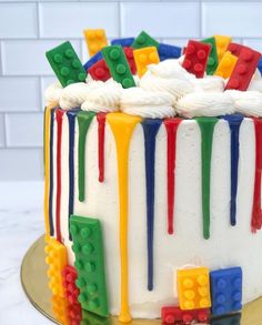 a cake decorated with legos and icing on a plate in front of a white brick wall